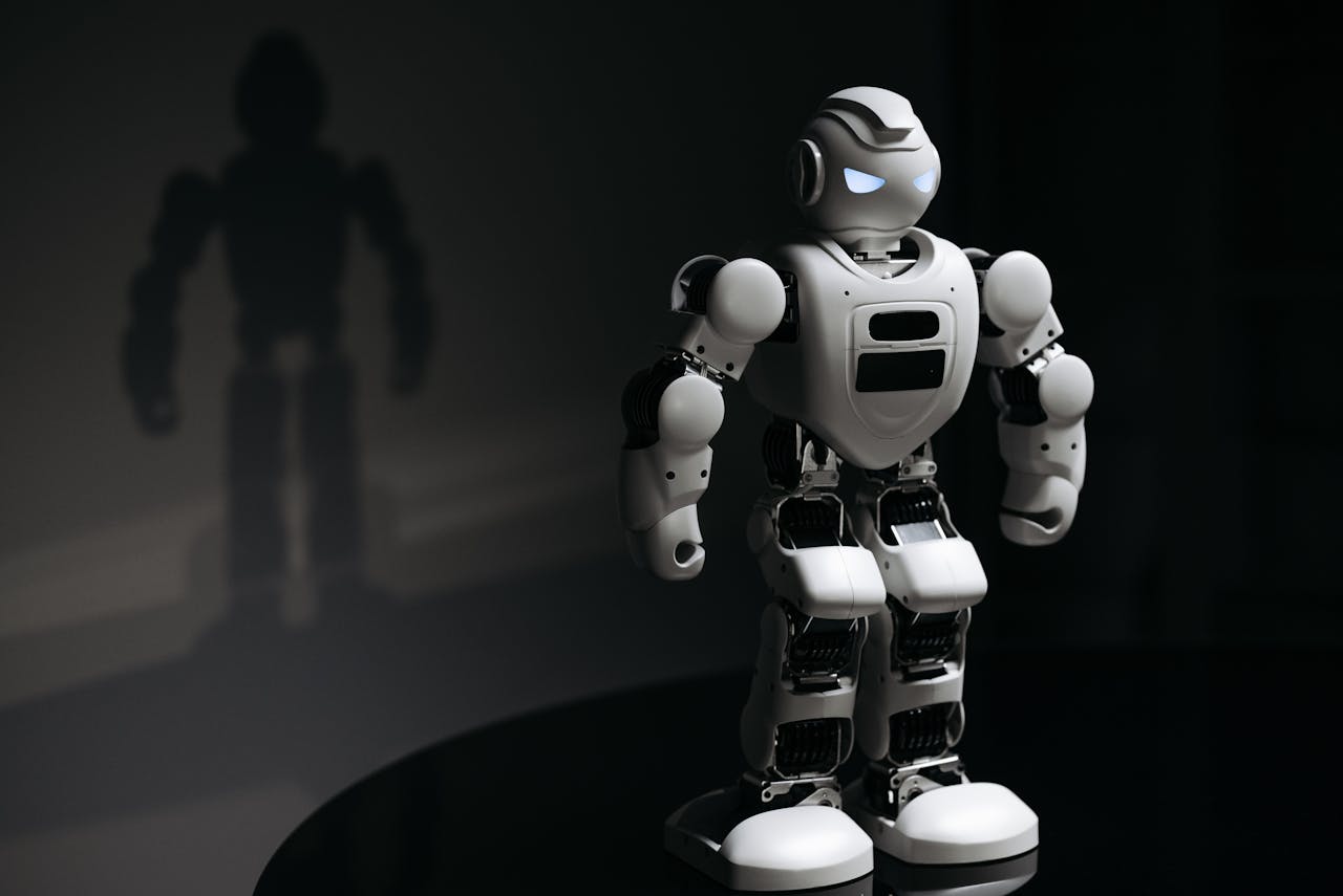 White robot toy casting a shadow in a dark studio setting, highlighting artificial intelligence.